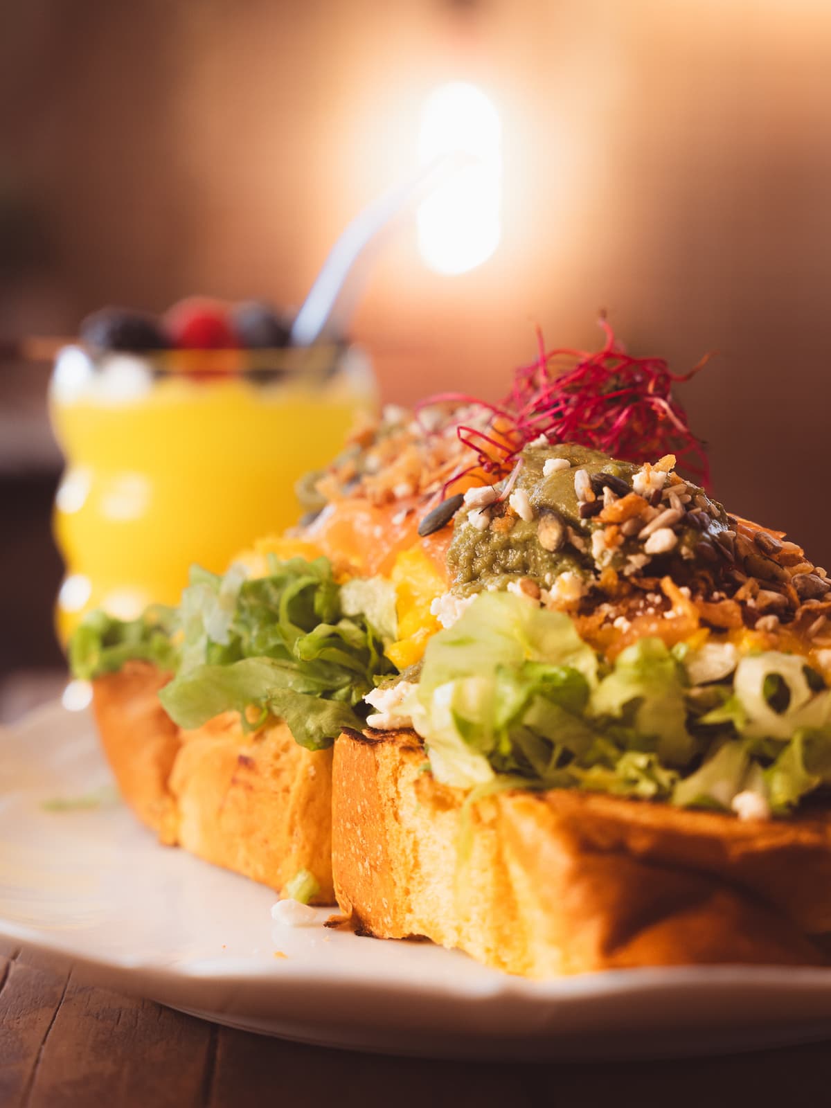Avocado toast on toasted brioche with scrambled eggs, smoked salmon, guacamole, seeds and beet sprouts