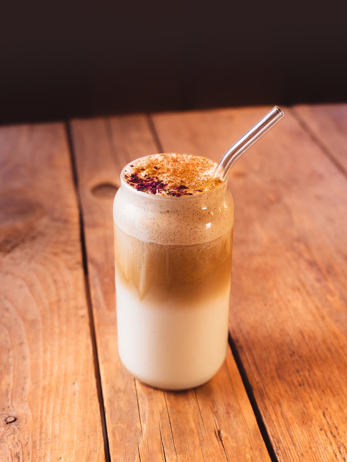 Chai latte topped with cinnamon and dried rose petals in a tall glass