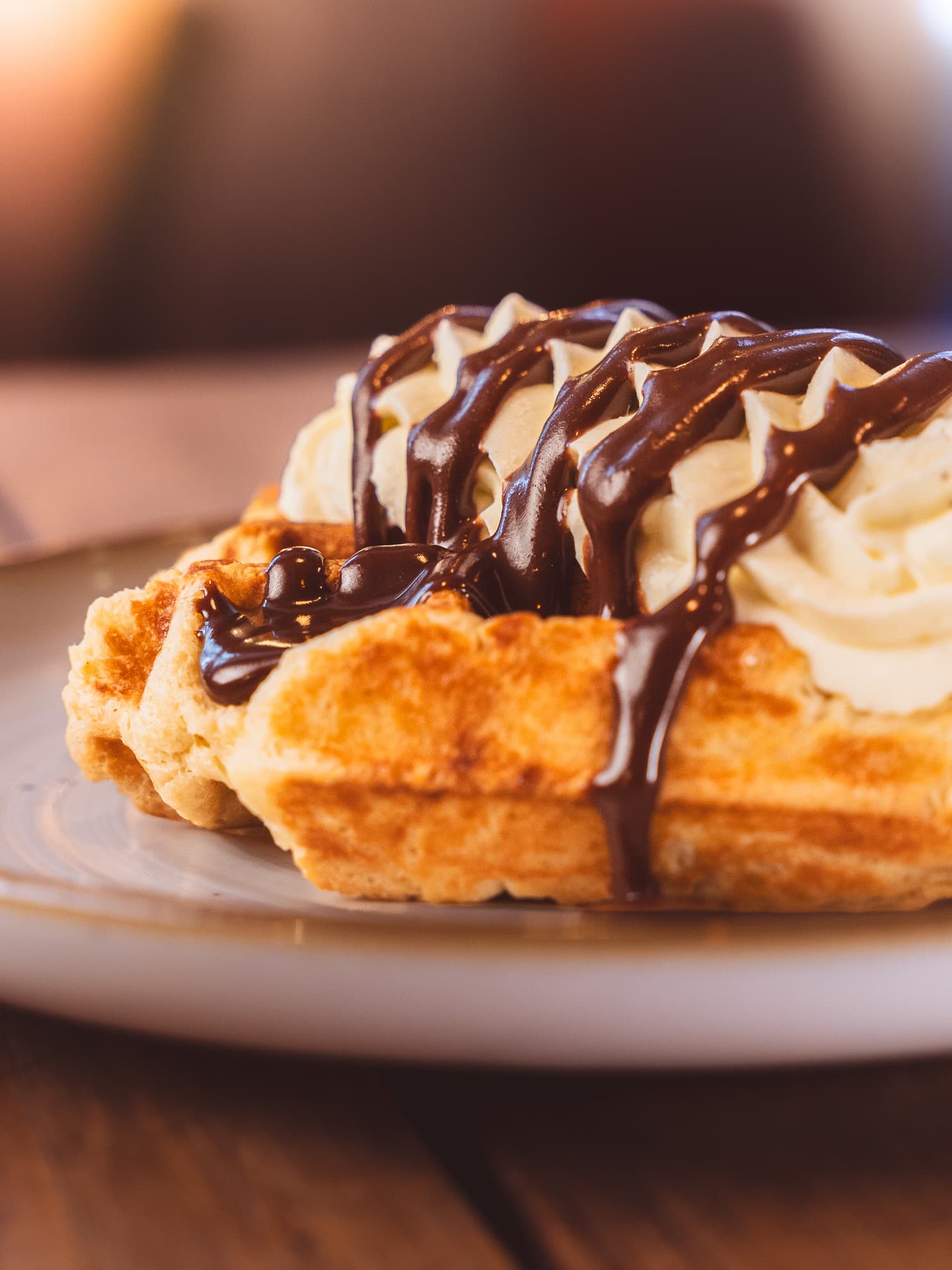 Waffle topped with piped whipped cream and chocolate sauce
