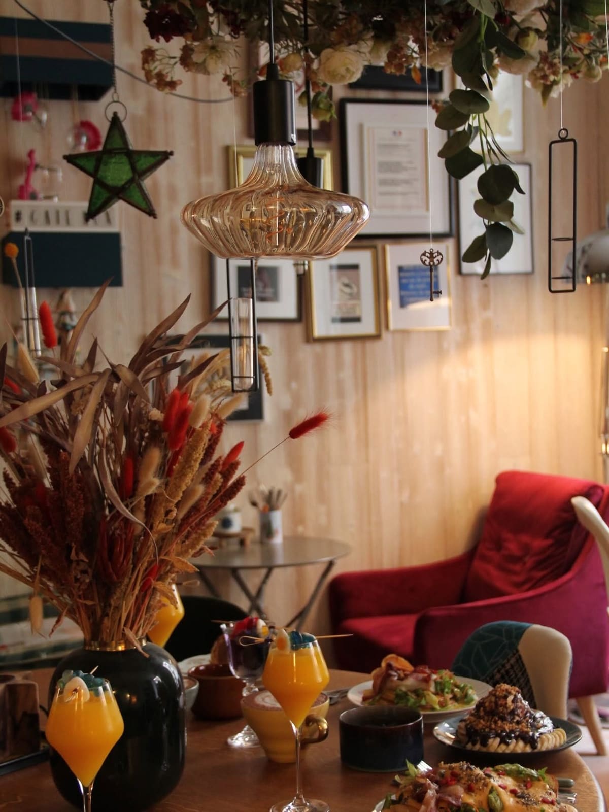 Inside Le Bar Roux d'Heure: hanging lamps, dried flowers and a red velvet armchair
